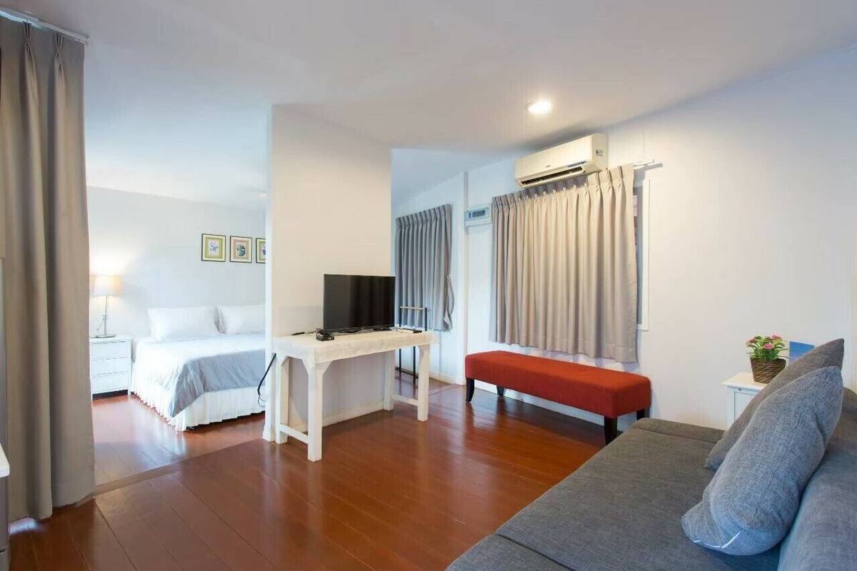 Une chambre d’hôtel comprenant un lit, un bureau avec une télévision, un canapé et un appareil de climatisation.