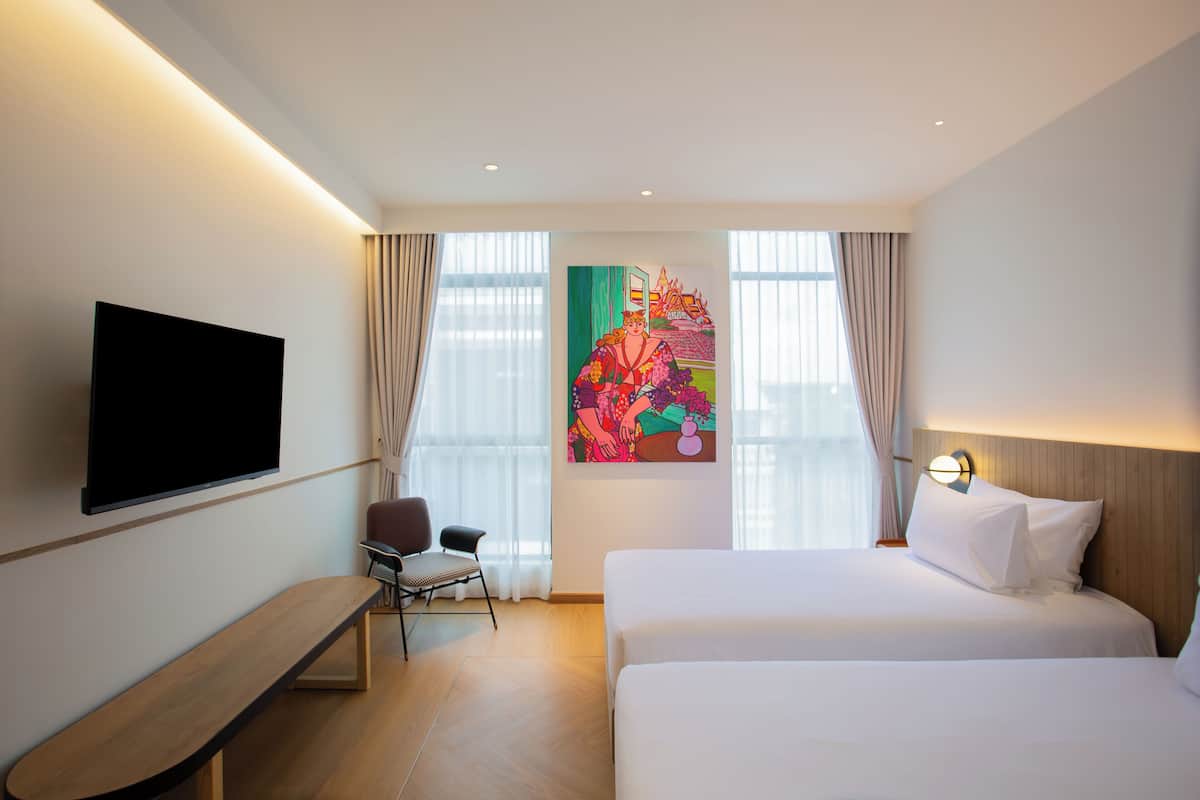 Une chambre d’hôtel avec un grand lit, un bureau, une chaise, un téléviseur à écran plat et un tableau au mur.