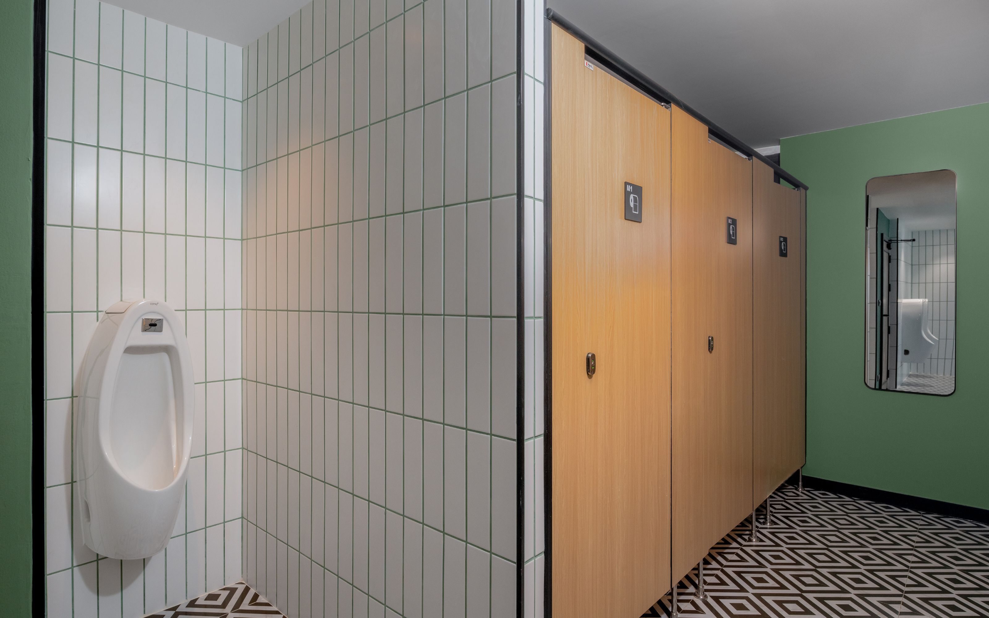 A men's restroom with a urinal, wooden stalls, and a mirror.