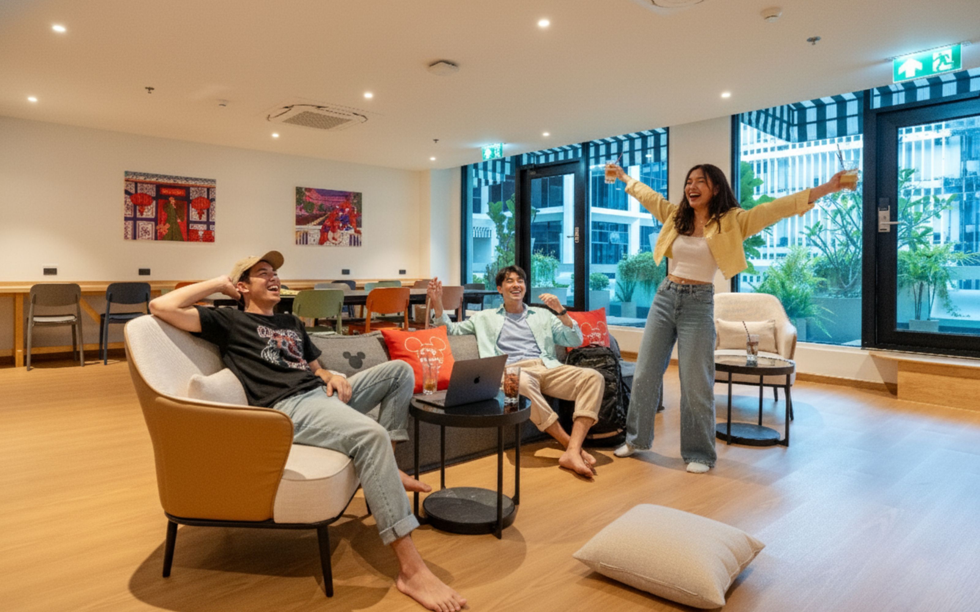 A modern lounge area with a sofa, chairs, a coffee table, and a laptop on a table.