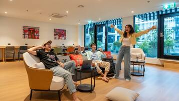 A modern lounge area with a sofa, chairs, a coffee table, and a laptop on a table.