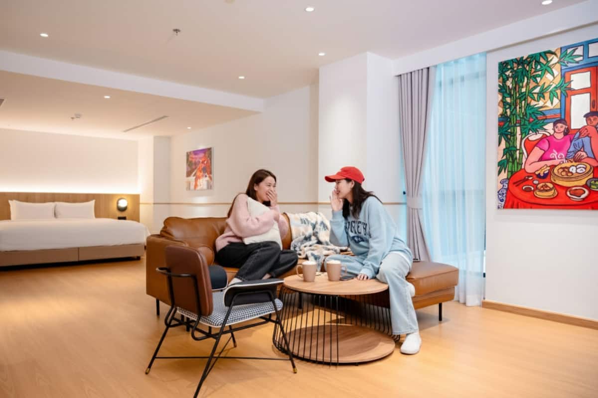 Une chambre d’hôtel moderne avec un grand lit, un canapé, une table basse et un tableau au mur.