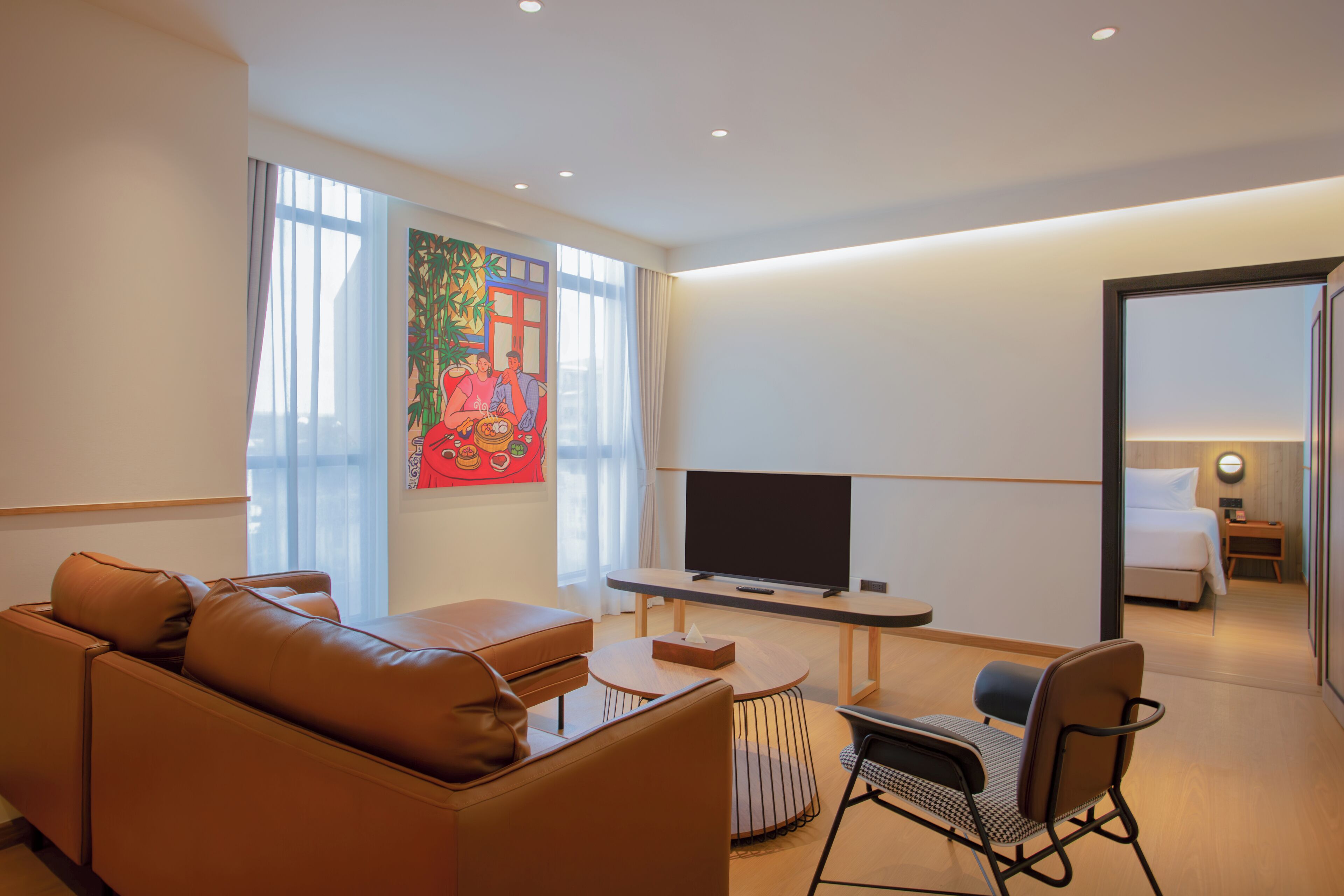 Una habitación de hotel moderna con sofá, televisor, una mesita y una silla.