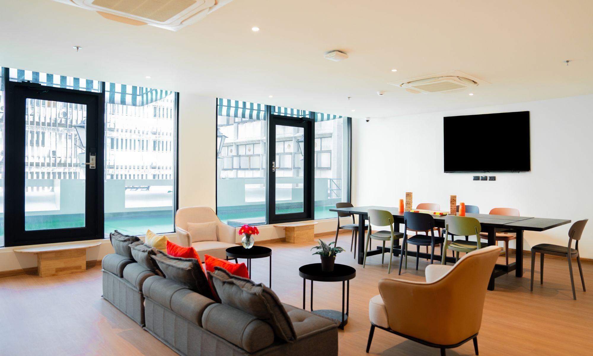 A modern living room with a sofa, chairs, a dining table, and a TV.