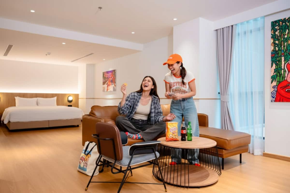 Une chambre d’hôtel moderne équipée d’un lit, d’un canapé, d’une table basse et d’une petite table à manger.