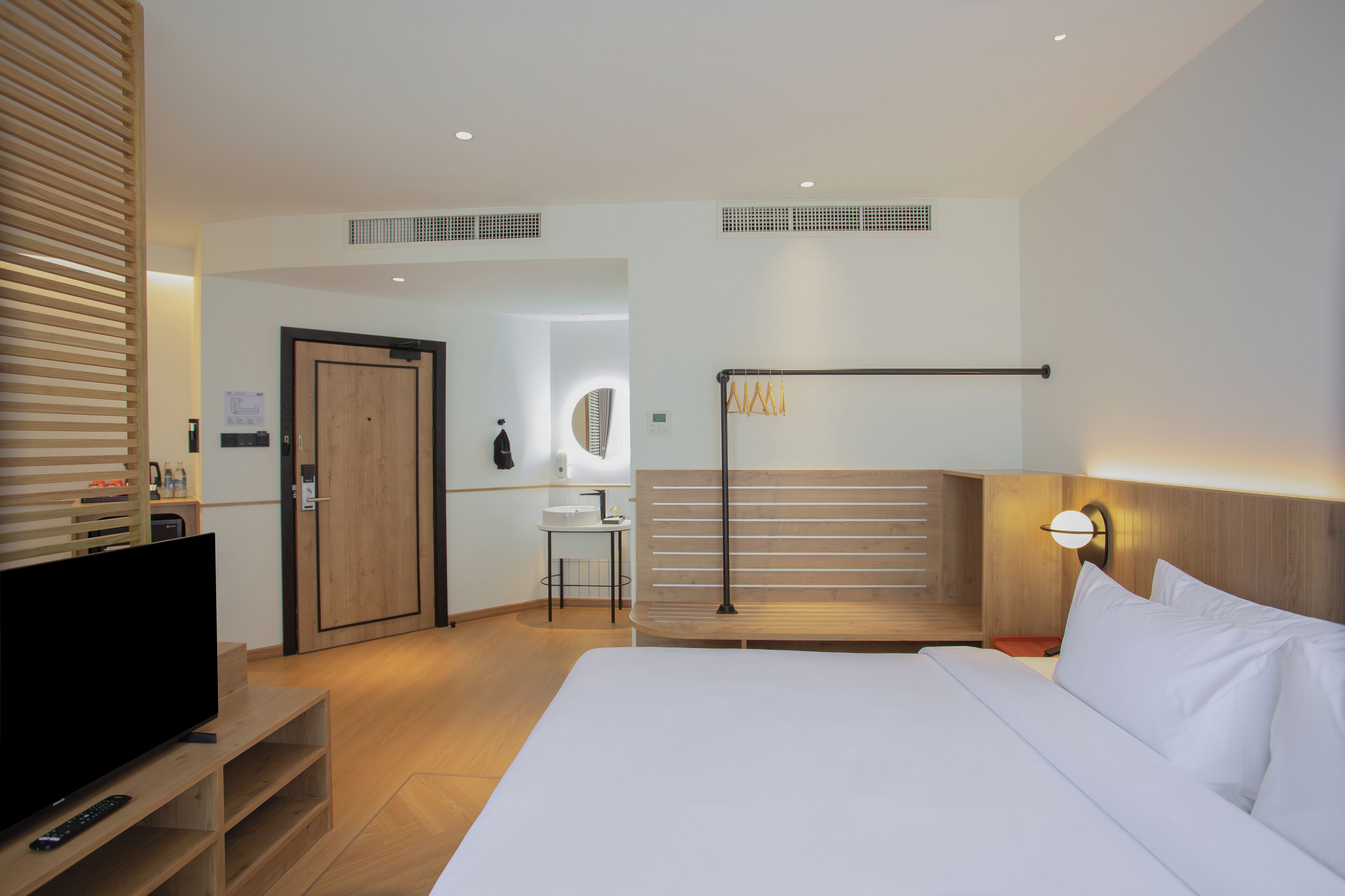 A modern hotel room with a large bed, a television, a desk, and a bathroom.
