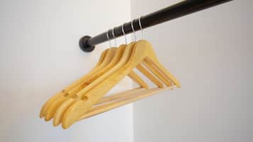 A wooden coat rack with multiple hangers against a white wall.