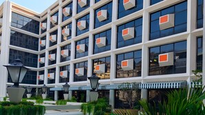 A multi-story hotel with a modern facade, large windows, and a landscaped courtyard with outdoor seating. - Lub d Bangkok Chinatown (Bangkok)