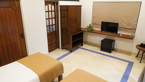 A bedroom with a bed, a wardrobe, a small TV on a shelf, and a desk with a computer. - Olive Hotel Alidia Beach Resort by Embassy Group (Baga)