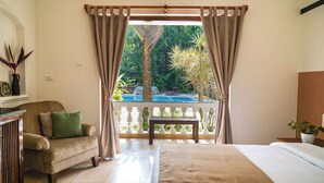 A bedroom with a view of a pool and tropical plants. - Olive Hotel Alidia Beach Resort by Embassy Group (Baga)