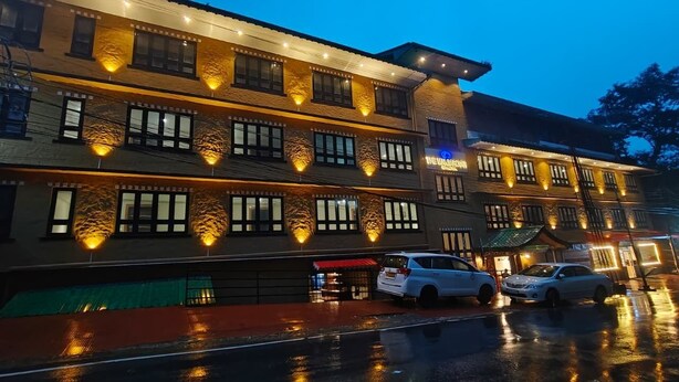 A multi-story hotel with a traditional architectural style, featuring multiple windows and a well-lit facade. - The Mansarovar Hotel & Banquet (Gangtok)