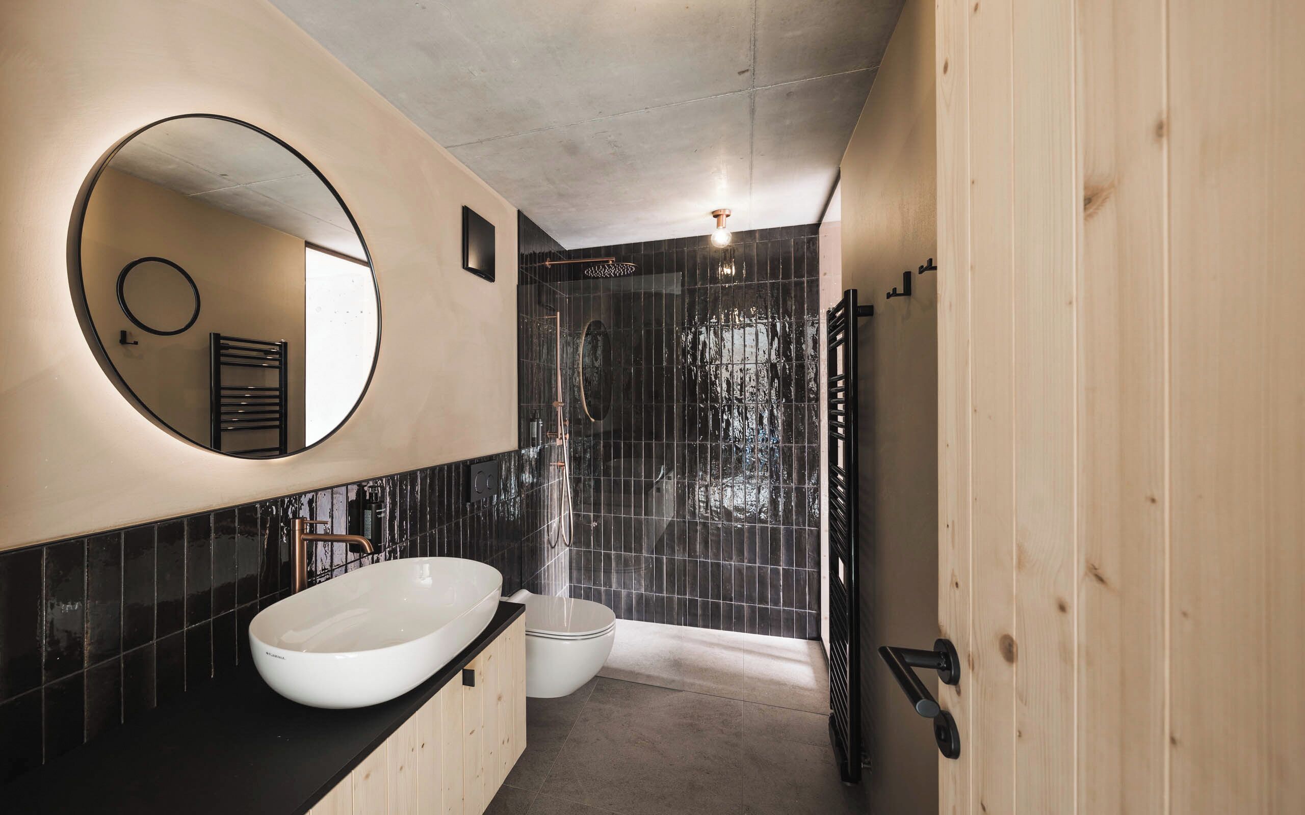 Une salle de bain moderne avec un grand lavabo ovale, un miroir rond et un espace douche.
