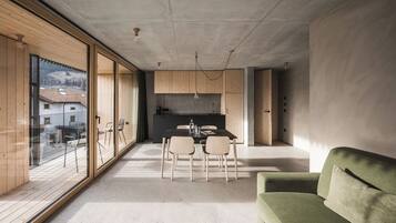Una cucina moderna con mobili in legno, una zona pranzo con tavolo e sedie, e un divano verde.
