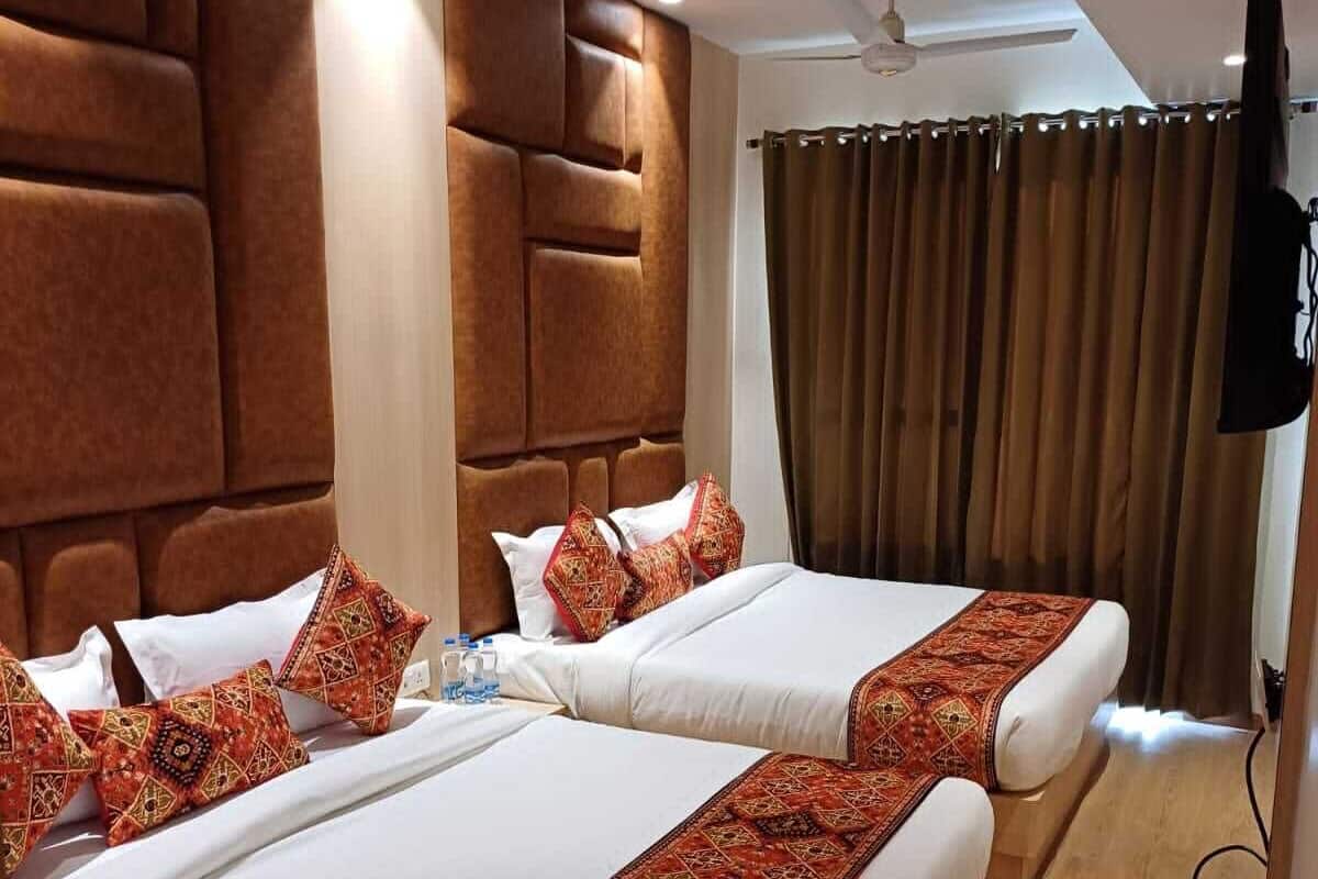 A hotel room with two beds, a modern headboard, a ceiling fan, and a television.