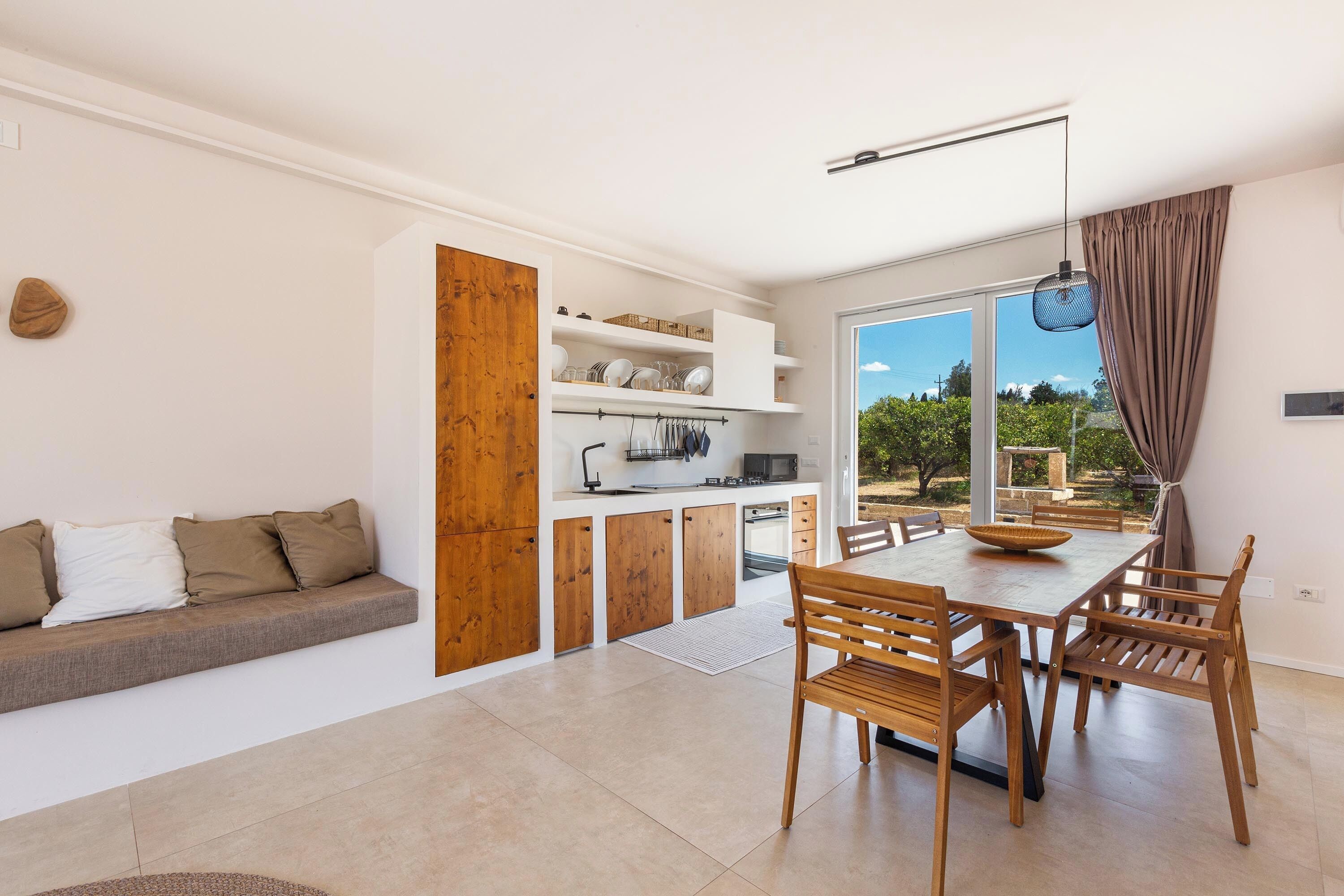 Una cocina moderna con armarios de madera, una mesa de comedor con sillas y un horno empotrado.