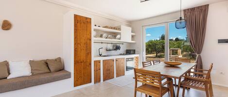 Una cocina moderna con armarios de madera, una mesa de comedor con sillas y un horno empotrado.