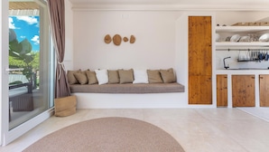 A modern living room with a built-in bench, a wooden cabinet, and a glass door leading to an outdoor area. - 4096 Villa Gabriella by Perle di Puglia (Sannicola)