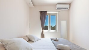A bedroom with a bed, pillows, a window with curtains, and an air conditioning unit. - 4096 Villa Gabriella by Perle di Puglia (Sannicola)