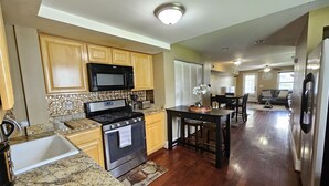 A kitchen with wooden cabinets, a stainless steel refrigerator, a microwave, and a stove.