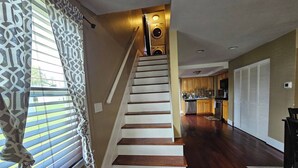 A staircase leading to a kitchen with wooden flooring and a patterned curtain.