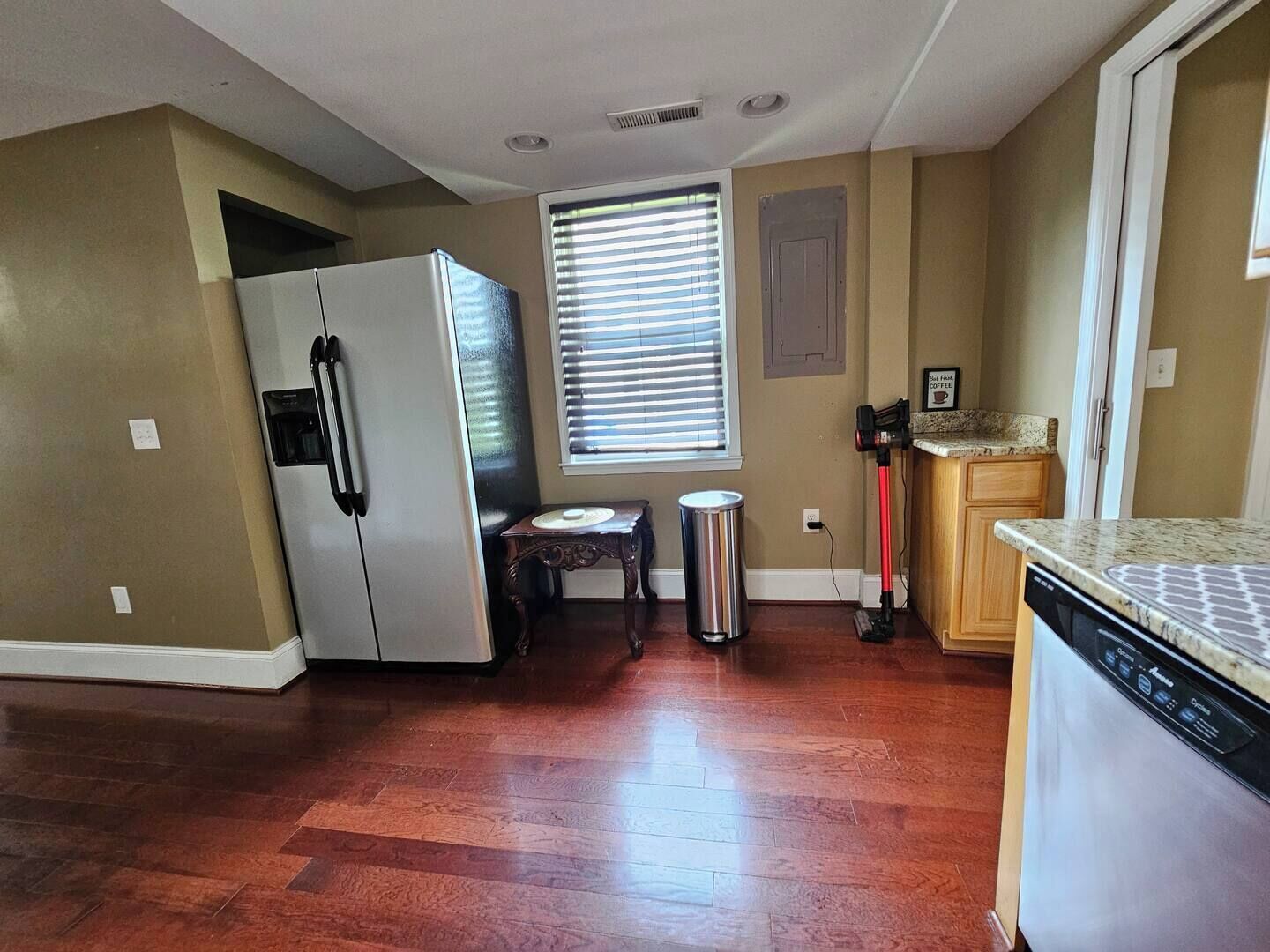 A compact kitchen with a refrigerator, a sink, and a window with blinds.