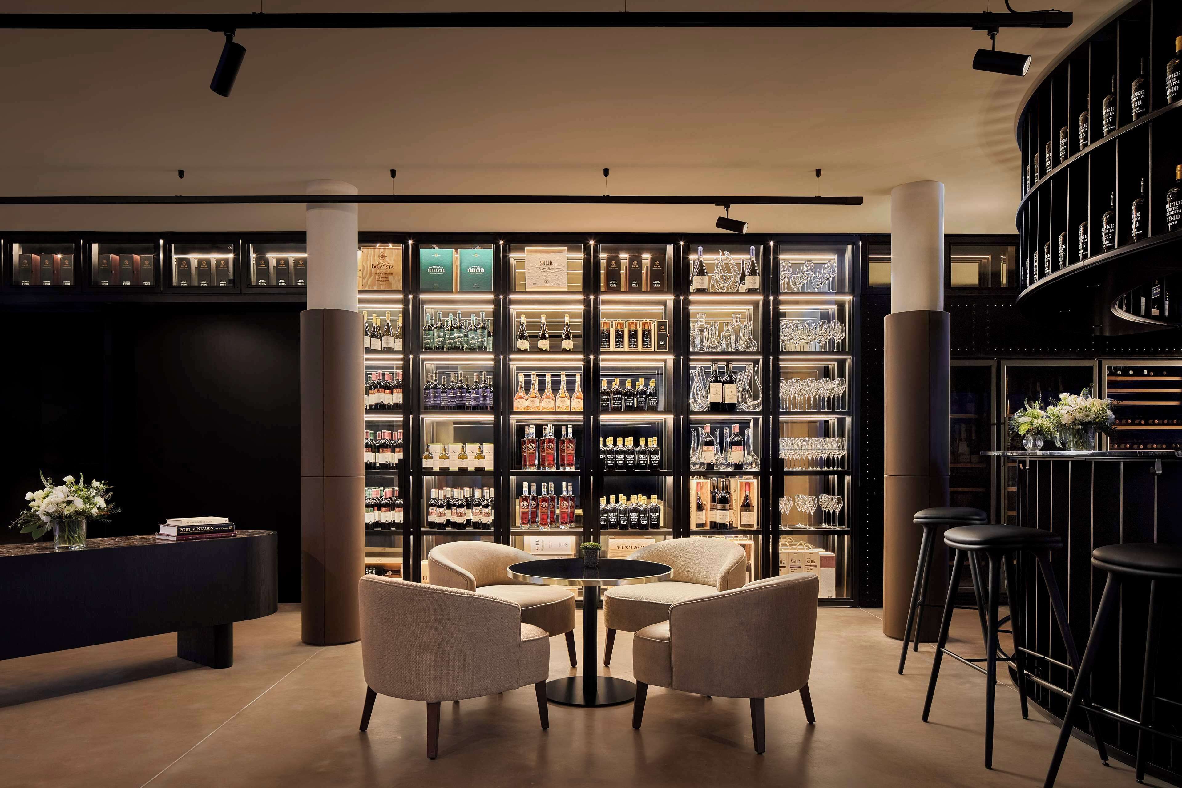 A bar area with a round table and two chairs, surrounded by shelves of liquor bottles and glasses.