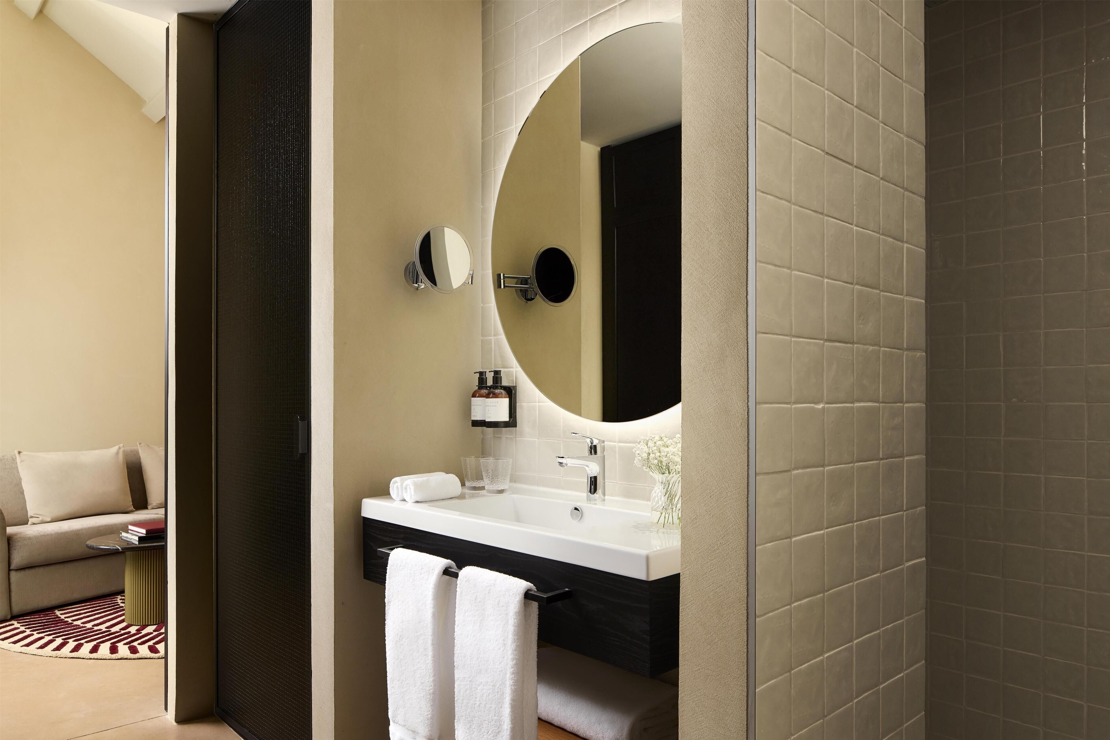 A modern bathroom with a large mirror, a sink, and a towel rack.