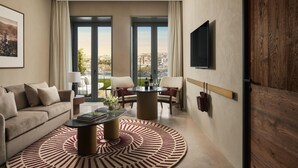 A modern living room with a sofa, a coffee table, and a TV mounted on the wall. - Tivoli Kopke Porto Gaia Hotel (Vila Nova de Gaia)