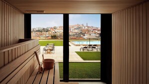 Ein modernes Zimmer mit einer Holzbodenverkleidung, einer großen Schiebeglastür zu einem Außenbereich mit Pool, Rasen und Blick auf die Stadt.