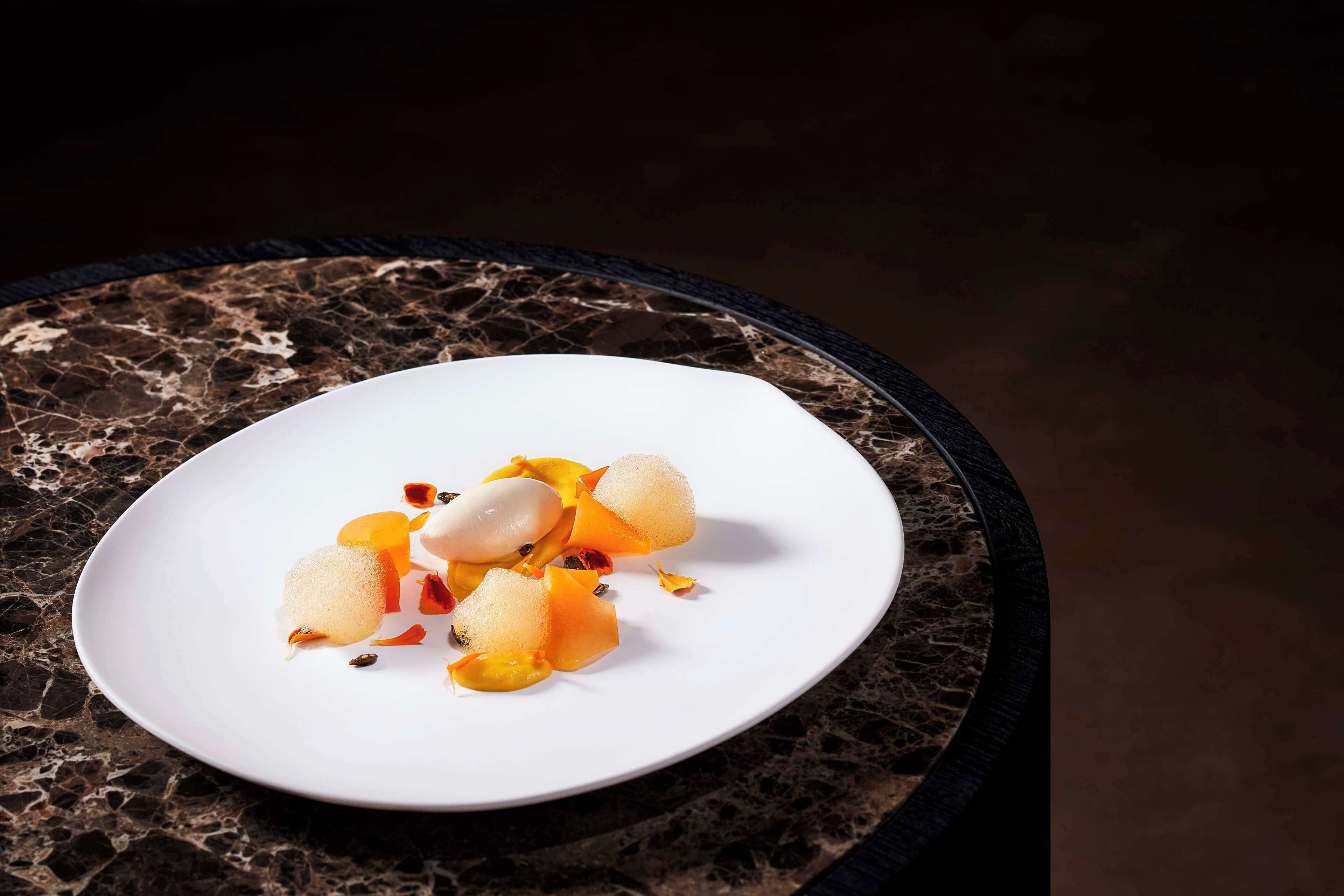 A white plate with a dessert on a dark marble table.