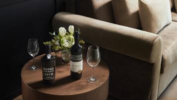 Una mesa redonda de madera con una botella de vino, una copa y un jarrón con flores.