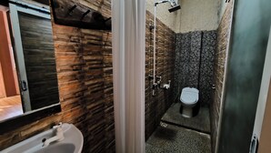 Une salle de bain avec un mur en pierre, des toilettes et un lavabo.
