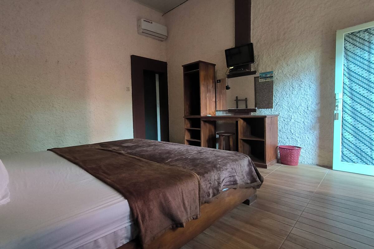 A bedroom with a bed, a TV, and a wooden desk.