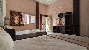 Une chambre avec deux lits, une télévision et une porte coulissante donnant sur un balcon.