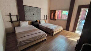 A room with two beds, a wooden floor, a textured wall, and a window with curtains. - New Lishafa Guesthouse (Karimun Jawa)