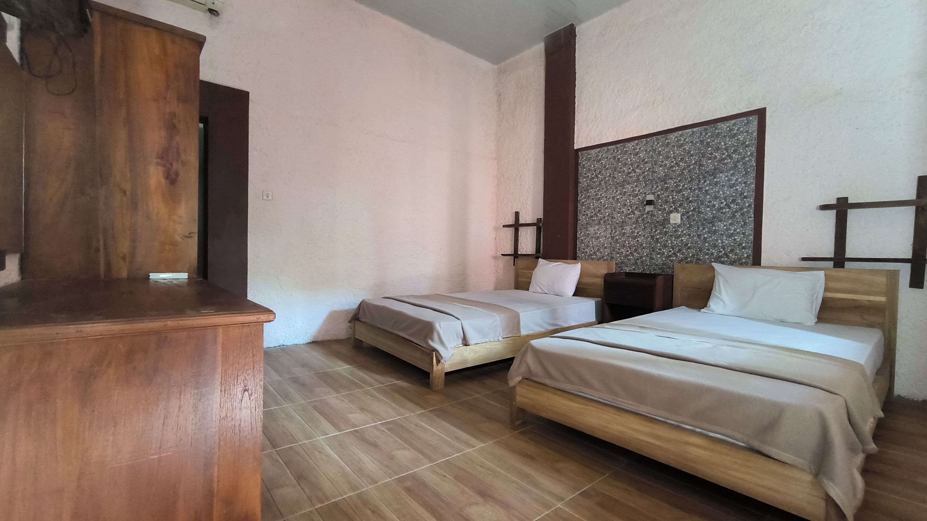 A room with two wooden beds, a wooden dresser, and a textured wall.