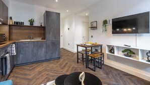 A modern kitchen with dark cabinets, a wooden countertop, and a dining area with a table and chairs.