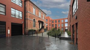 A courtyard with brick buildings, a covered walkway, and a statue.