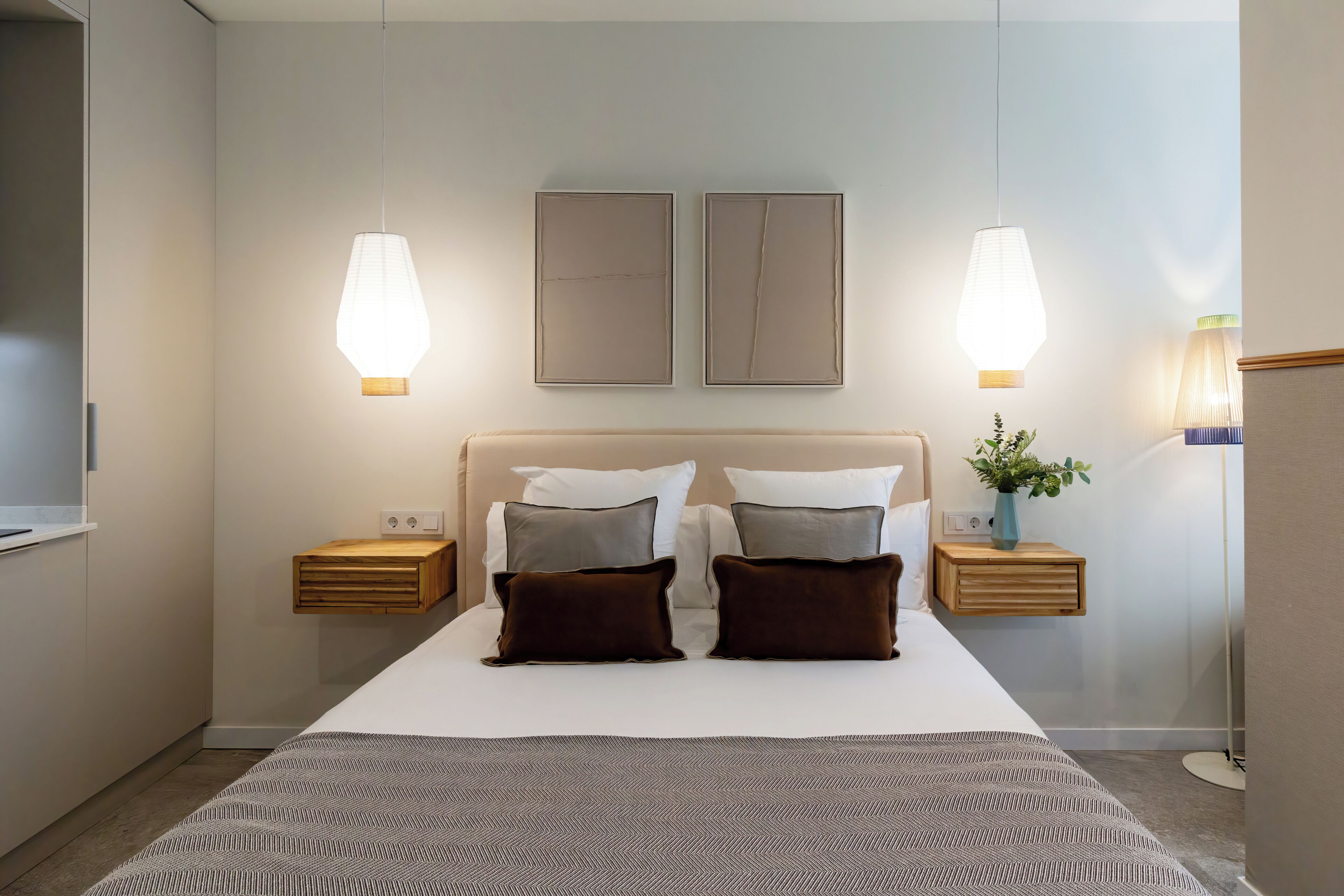 Et moderne hotelværelse med en stor seng, to sengeborde, et natbord, et vægmonteret fjernsyn og to vægmonterede lamper.