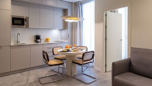 A modern kitchen with a dining area, including a round table, chairs, and a sofa. - Feelathome O'Donnell Apartments (Seville)