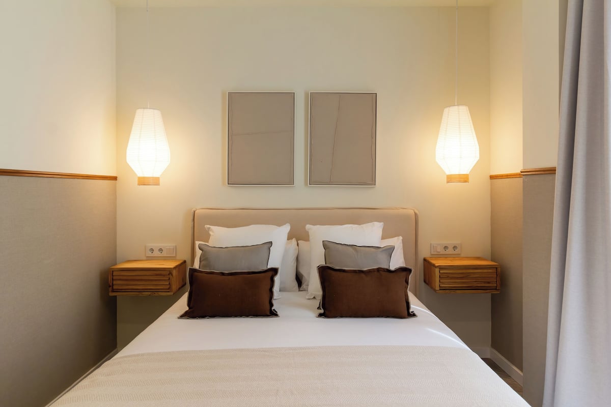 Un letto rifatto con due cuscini, una testiera e due comodini con lampade.