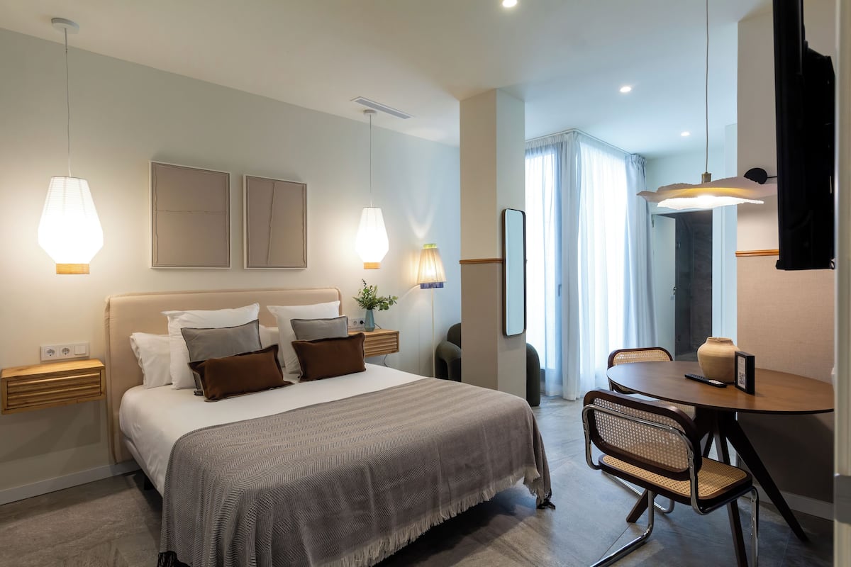 Una moderna camera d'albergo con un letto grande, comodini, una scrivania con una sedia e un angolo ristoro.