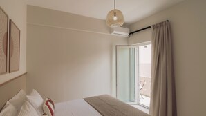 Et hotelværelse med en seng, en pendel, et vindue med gardiner og en dør til en balkon.