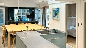 Eine moderne Küche mit Kochinsel, Esstisch aus Holz und Pendelleuchten.