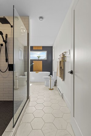 A modern bathroom with a glass shower enclosure, a white toilet, a bathtub, and a toilet paper holder. - NEW Golfers Dream Modern Patio King Bed (St. John's)