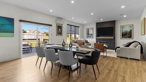 A modern living room with a dining area, a fireplace, and large windows. - NEW Golfers Dream Modern Patio King Bed (St. John's)