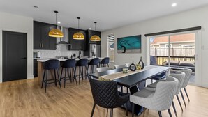 A modern kitchen with dark cabinets, a central island, and pendant lighting. - NEW Golfers Dream Modern Patio King Bed (St. John's)