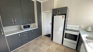 A kitchen with grey cabinets, a white refrigerator, an oven, and a microwave. - Close to Trade Central Mall, 3 Bedrooms, Sleeps 6, Wheelchair friendly (Rotorua)