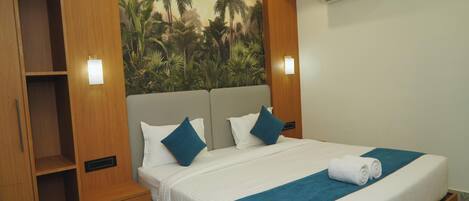 A hotel room with a bed, a wooden wardrobe, a nightstand, and a wall-mounted air conditioner.