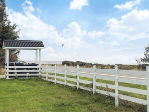 A white gazebo with a metal roof, a white fence, and a grassy area with a road in the background. - 4 Star Holiday Home in Vestervig (Vestervig)